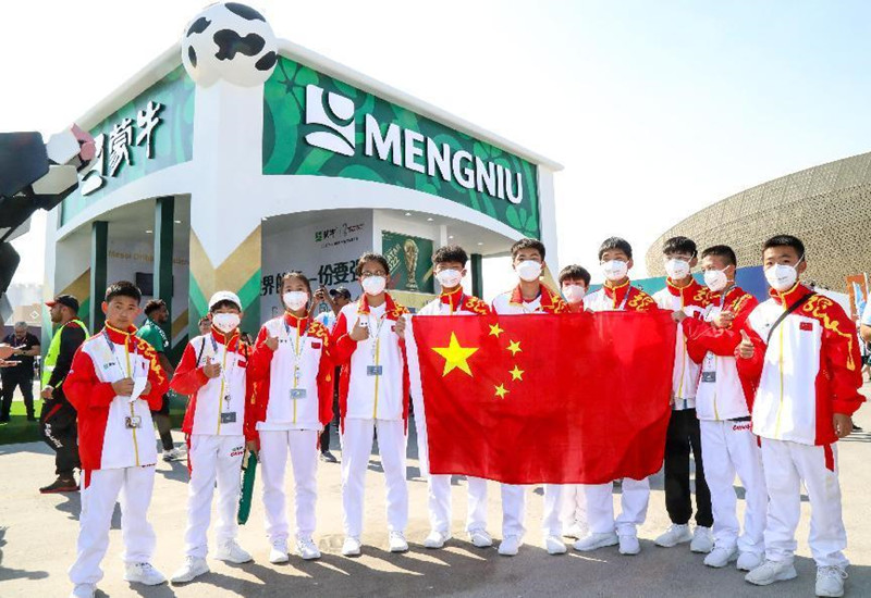 “出征”卡塔尔的11名中国足球少年（右四为牛甲埼）在多哈与国旗合影。 郧轩文摄
