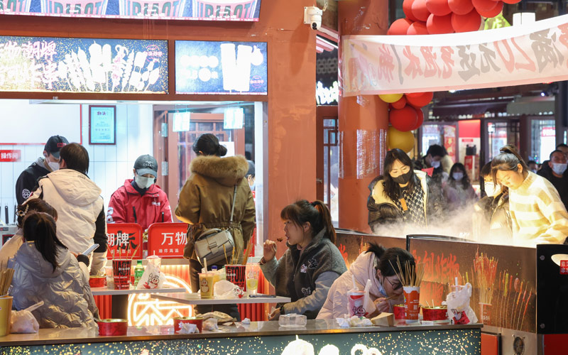 2023年1月8日傍晚，众多市民和游客在湖北襄阳古城购买品尝美食。
