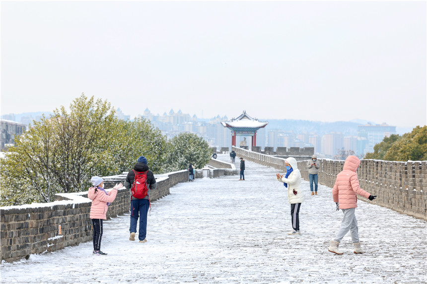 1月15日，市民在湖北省襄阳古城城墙上赏雪游玩。 