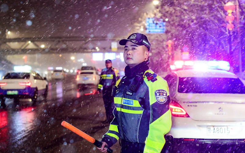江岸交警在雪中指挥车辆通行。