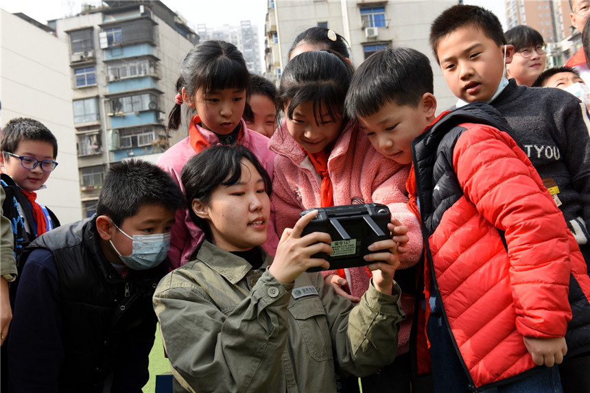 青年志愿者向学生讲授无人机操作方法。