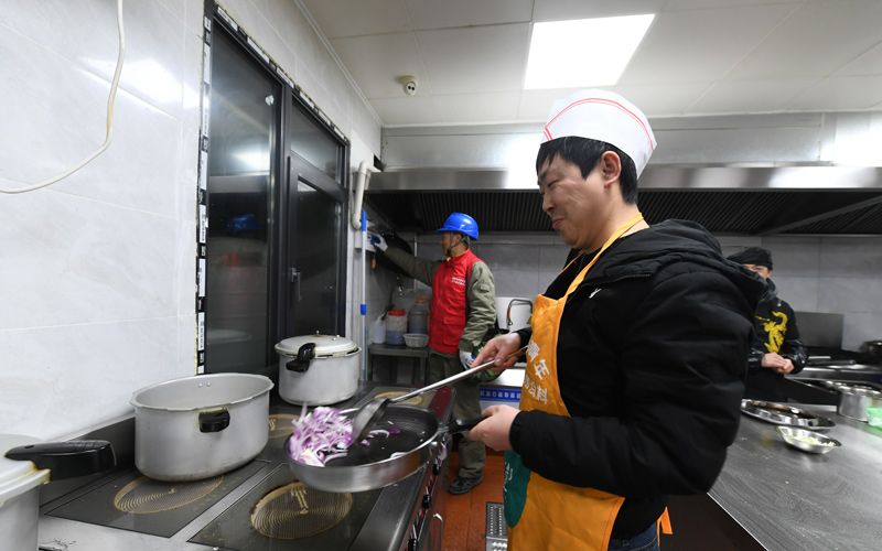 鸾英寨饭庄全电厨房，厨师们正在电炒炉上炒菜。涂坦摄