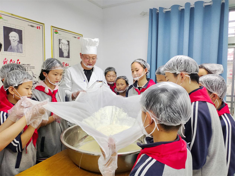 郧西县羊尾镇中心小学学生在“非遗”传承人涂海波的指导下制作“板桥豆干”。徐军摄