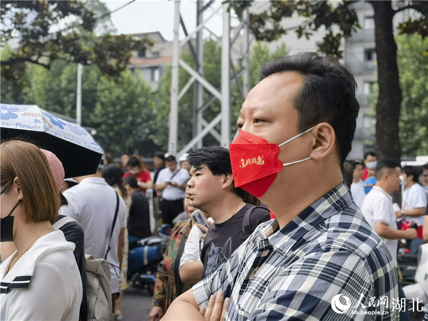 在武汉市第二十六中学考点外，送考家长戴着印有“金榜题名”的口罩。人民网记者 周雯摄