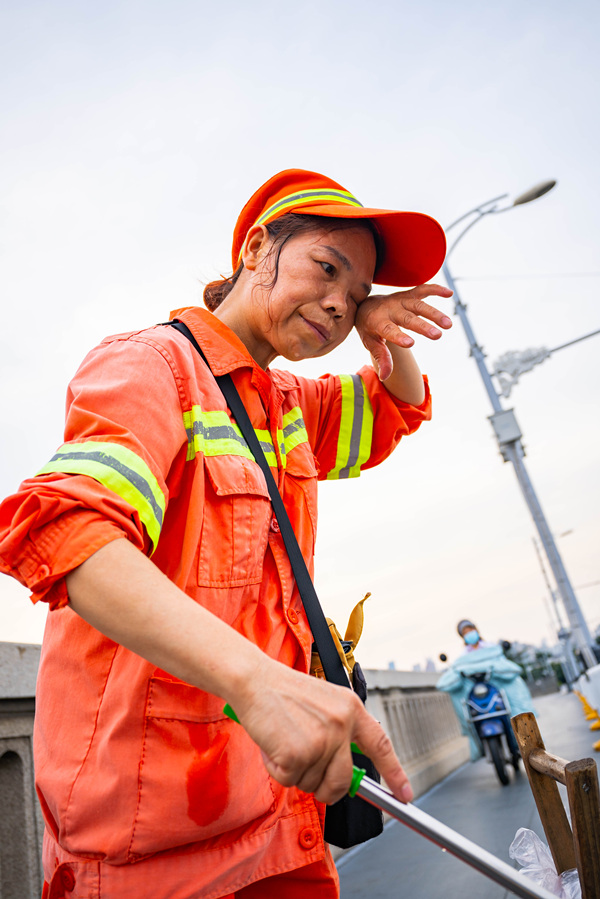 高溫下，環衛工人在武漢長江大橋上保潔，“汗”衛城市文明。詹重山攝