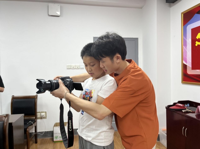 小朋友向志愿者学习摄影技术