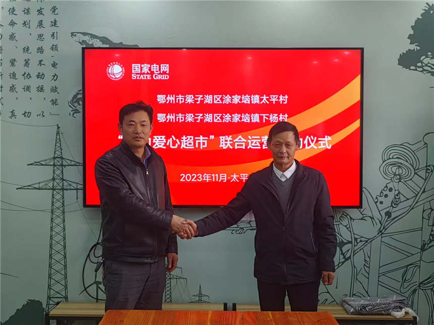 太平村、下杨村联合运营“电力爱心超市”，太平村支部书记王忠能、下杨村支部书记夏国煌握手合影。段浪摄