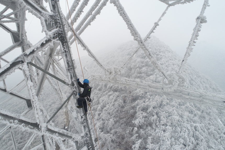 電力應急處置人員爬上70米高的±800千伏陝武輸電線路1898號塔，通過機械震動方式清除地線和光纜上的積雪。鄒小民攝 