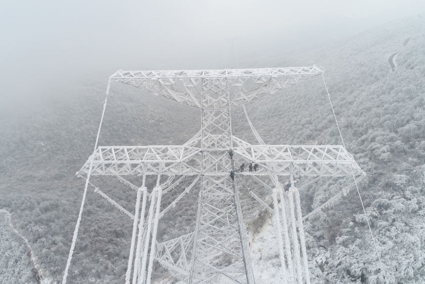 電力應急處置人員爬上70米高的±800千伏陝武輸電線路1898號塔，通過機械震動方式清除地線和光纜上的積雪。鄒小民攝