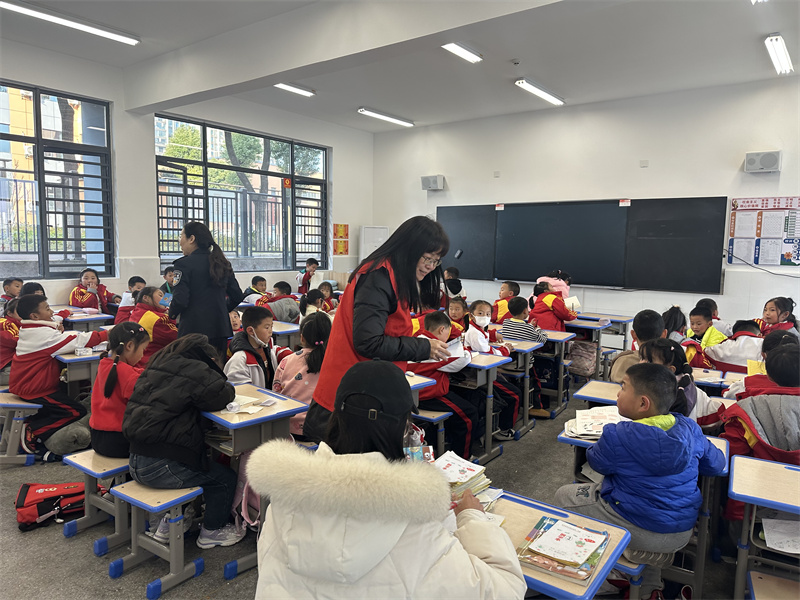    志愿者向小学生宣传和发放《致广大家长的一封信》。肖依摄