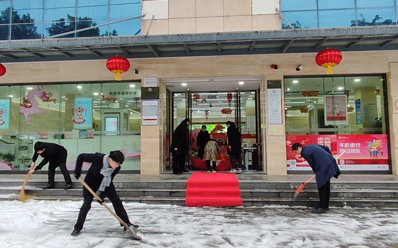 网点员工分工合作在网点门前铲雪除冰。