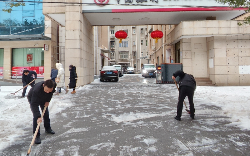 网点员工分工合作在网点门前铲雪除冰。