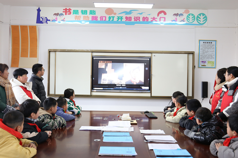 党员志愿者与孩子们一同观看《雷锋事迹》精彩片段。