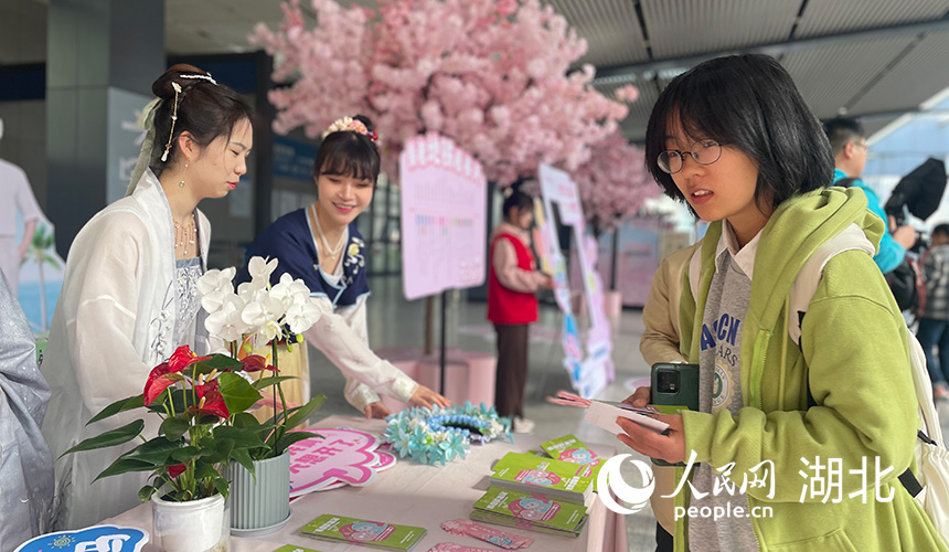 在武汉地铁1号线黄浦路站，穿着汉服的小姐姐向市民介绍地铁赏花路线图和美食打卡地。人民网记者 周恬摄