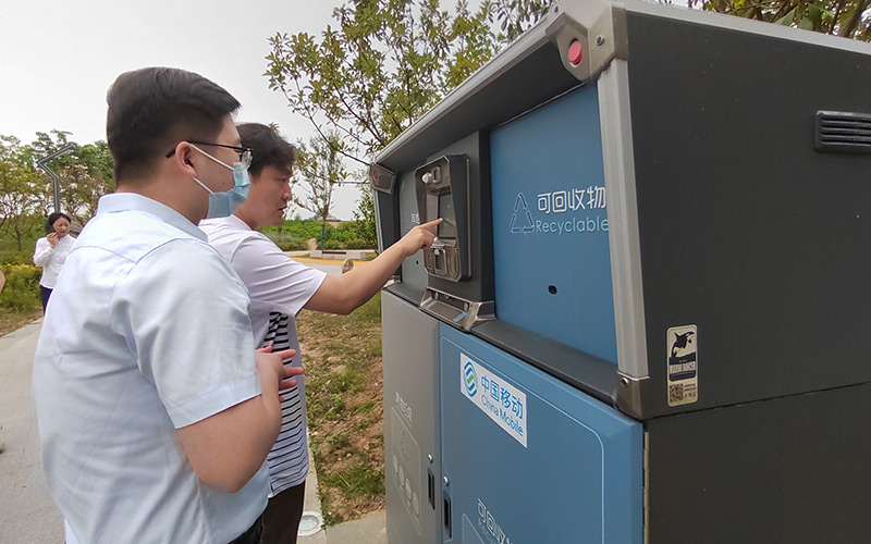 市民正在使用襄州区民发广场上湖北移动投运的一台5G智能垃圾箱