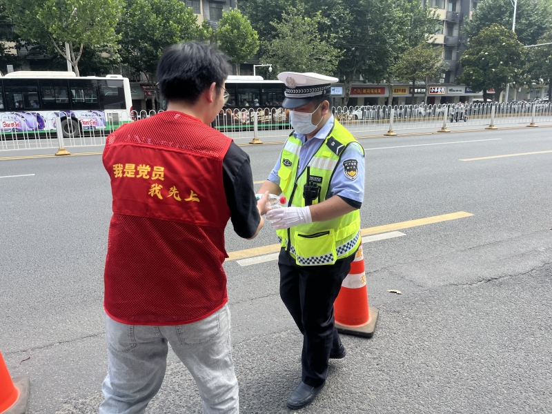 2023年高考期间，硚口烟草志愿者为考场外执勤的警员送水。