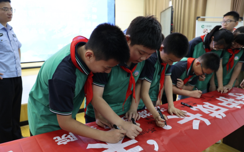 洪湖市實驗小學學生在宣傳橫幅上簽字，承諾遠離煙草制品。