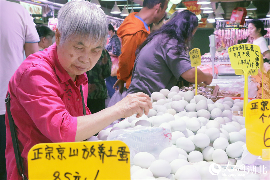 5月30日上午，一位老人在洪山广场地铁站菜市场挑选鸡蛋。人民网记者 周恬摄