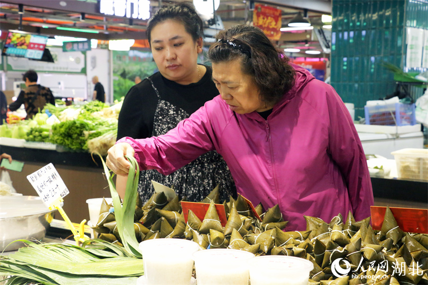 端午将至，洪山广场地铁站菜市场摆出了粽叶、手工粽子等节日美食，供市民挑选。人民网记者 周恬摄