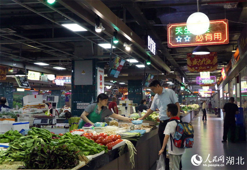 下班后，家长接到孩子，顺便在地铁菜市场买个菜。人民网记者 周恬摄