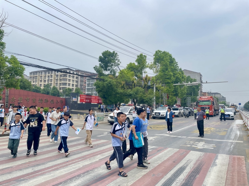 官塘驿中队交警截停车流，形成安全屏障，守护小学生上放学路。