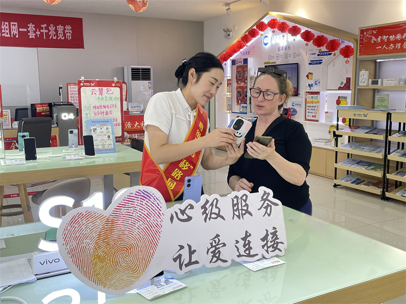 在武当山太和路营业厅 工作人员帮助外籍游客卡罗尔办理入网业务