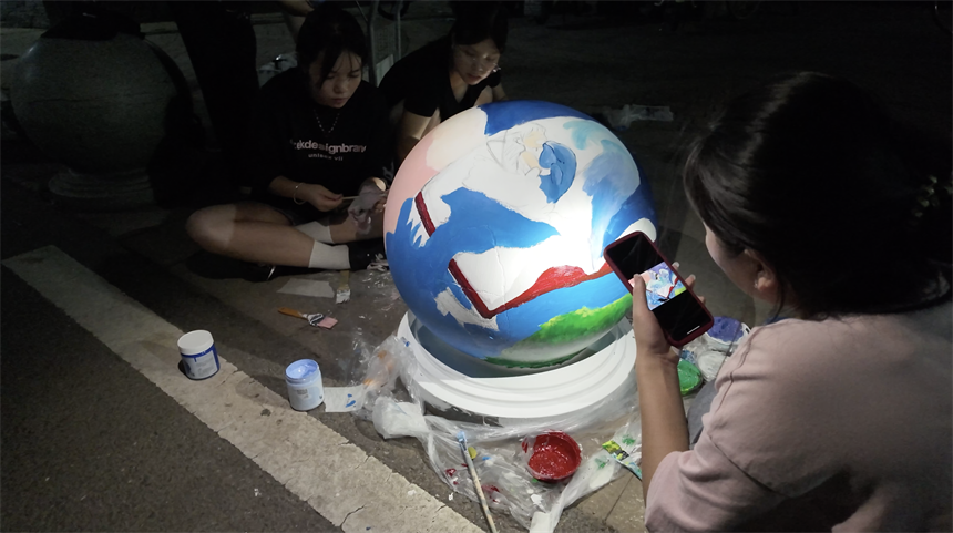 武汉学院的大学生志愿者在绘制石墩。