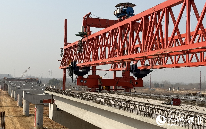 鄂州花湖机场高速公路二期工程临空经济区互通主线桥施工现场，架桥机正在落梁。人民网记者 周恬摄