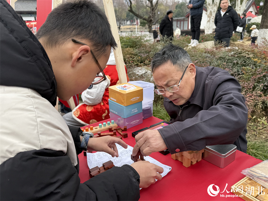 男孩正在体验错格全对称鲁班锁玩法。人民网记者 周恬摄