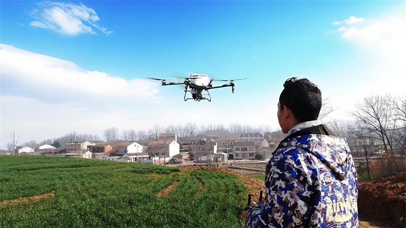 基于优质的移动5G网络，“新农人”操作无人机在田间施肥。