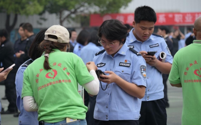 在志願者的引導下，參與獻血的學生們正在手機上登記填表。武漢警官職業學院供圖