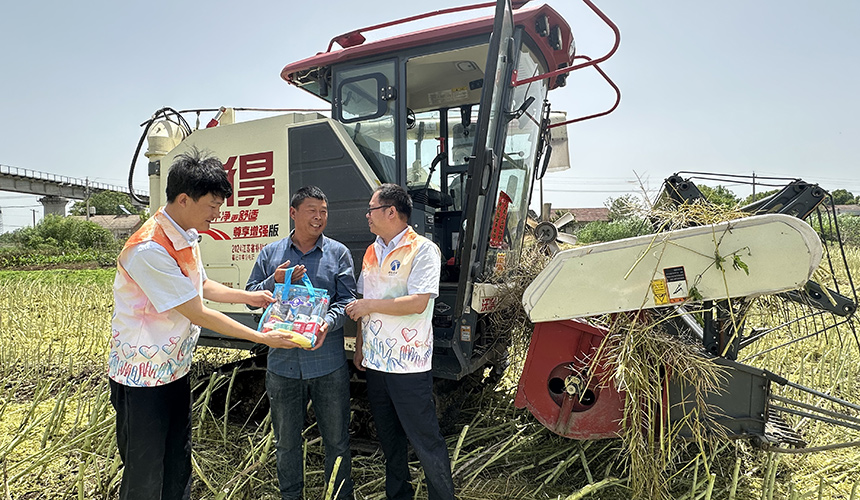 随岳运营公司组织志愿者给联合收割机司机送消暑饮品。