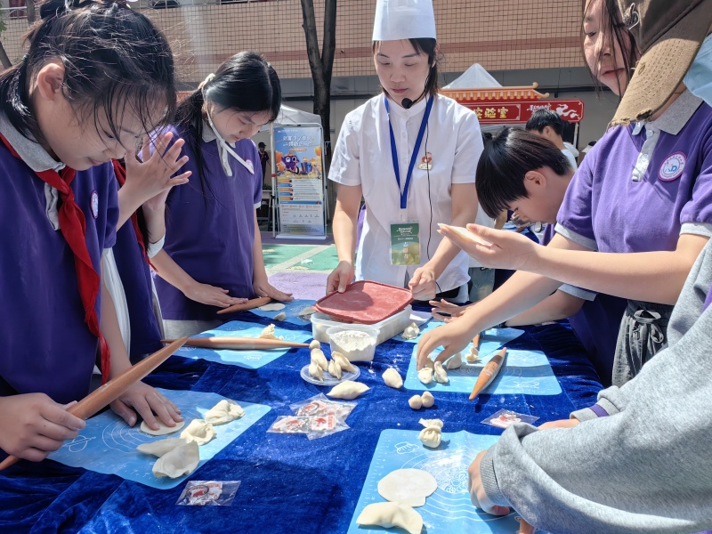 学生们和街道社区、家长志愿者一起包饺子。