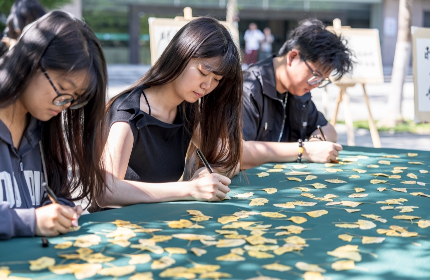 学生在银杏叶上手写寄语 。苏古润摄