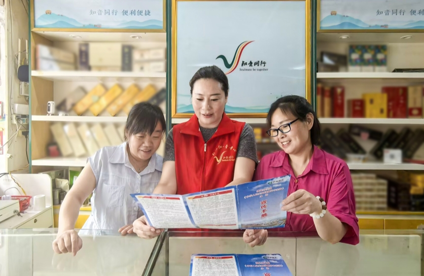 6月4日，十堰市郧阳区烟草专卖局普法志愿者（中）到零售商店，通过入户讲解、发放普法手册的方式开展普法宣传。陈光霞摄