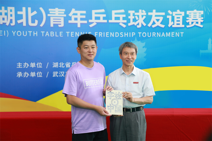 學校校長孔建益向台灣乒乓球代表團領隊柯建利贈送《字繪中國》書籍。