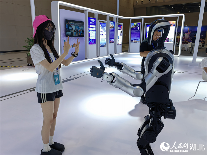 参会嘉宾与服务外包企业带来的人形机器人互动。人民网记者 郭婷婷摄