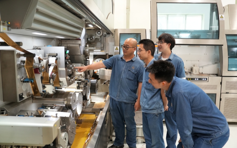 卷包车间青年员工在机台讨论设备操作重难点。