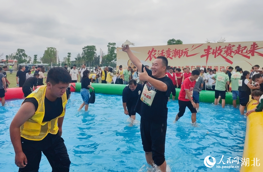 “鱼跃丰年”比赛中，选手高兴地展示自己抓到的鱼。人民网记者 郭婷婷摄