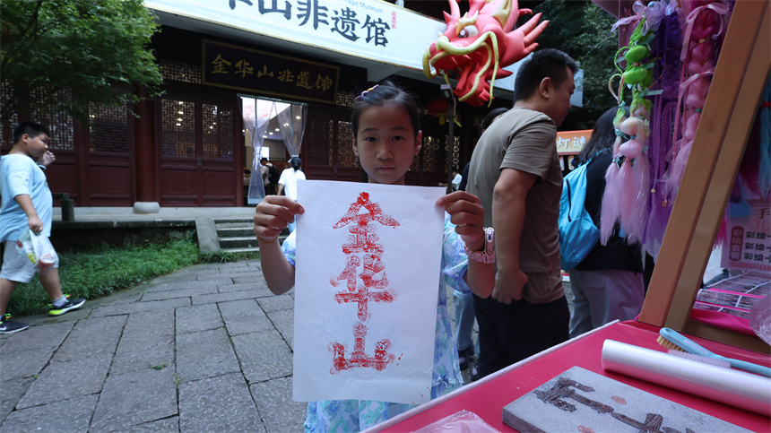 一名游客在景区手拿字绘“金华山”作品合影