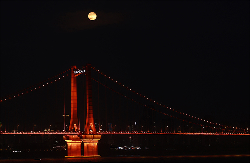 “超级月亮”与鹦鹉洲长江大桥的灯光交相辉映。彭昀迪摄