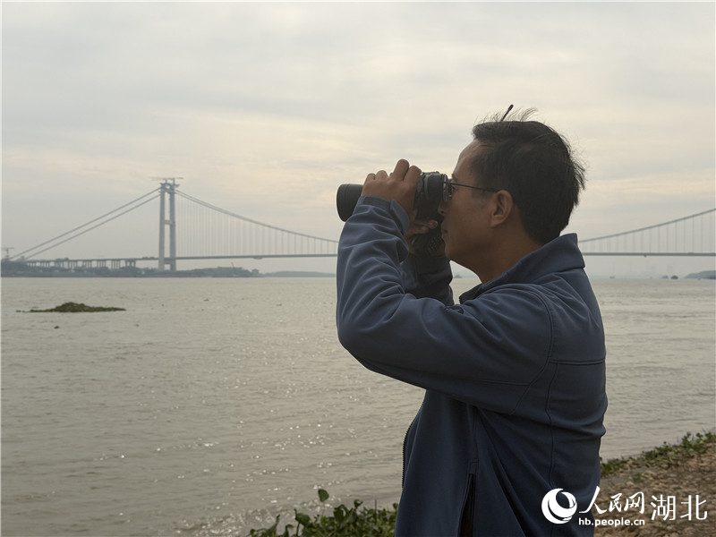 徐建利在江边观测江豚。人民网记者 张沛摄