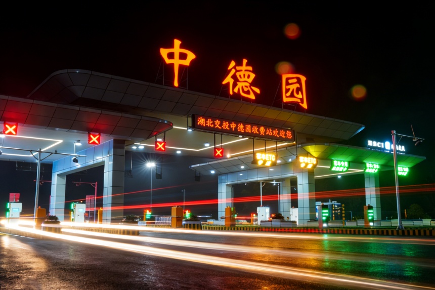 凌晨时分，京港澳高速中德园收费站灯火通明，红色的站名标识与车道间的车流光轨交相辉映。