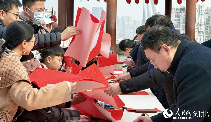 市民游客拿着空白的红纸争相请书法家写福字。人民网记者 周恬摄