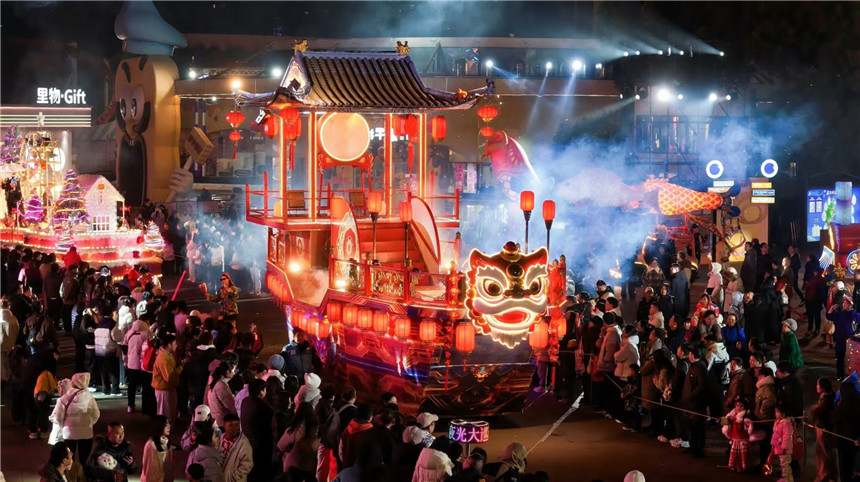 武汉欢乐谷喜气盈门夜光大巡游现场，飞天鳌鱼领衔，光影彩车随机飘雪，NPC热闹互动，年味拉满。
