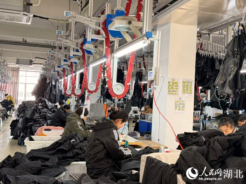 湖北奧瑟夫制衣有限公司的車間裡，四條銀灰色的“空中走廊”——吊挂系統有序運轉。人民網記者 張雋攝