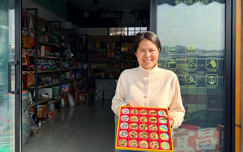 陳麗在店門口展示景區紀念幣。