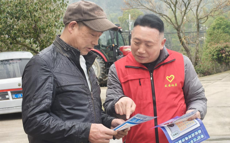 咸安区烟草专卖局志愿者为村民发放法治宣传单。