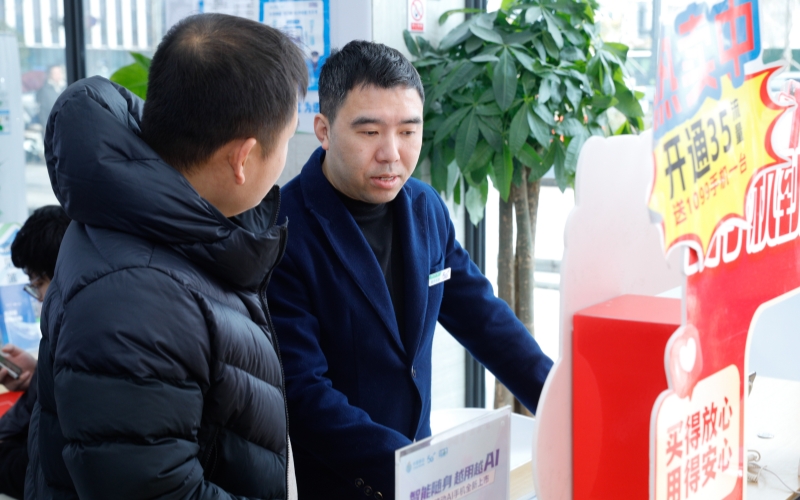 中國移動工作人員向客戶介紹AI手機和“以舊換新”活動。