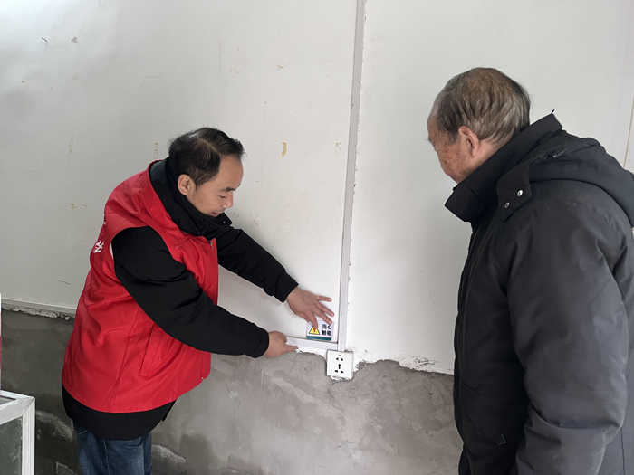 （客户经理帮助老年零售户粘贴安全用电警示标语。张姮摄